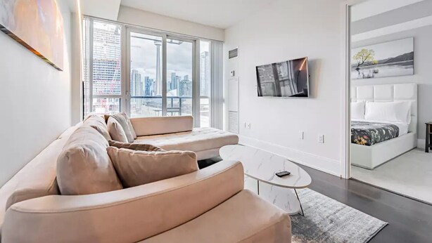 Una sala de estar moderna con un sofá, una mesa de centro y una cama con vista a la ciudad.