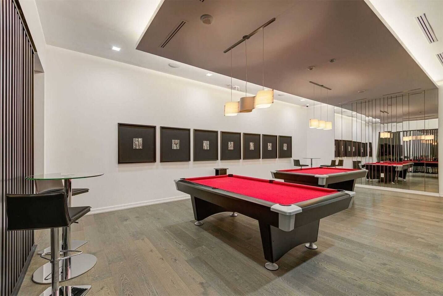 Een modern binnenzwembad met meerdere pooltafels, kunstwerken aan de muren en een eigentijds plafondontwerp.