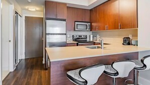 Una cocina moderna con armarios de madera, electrodomésticos de acero inoxidable y una barra con taburetes.