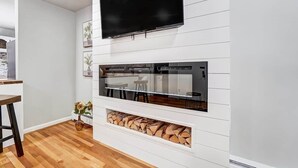 Ein modernes Wohnzimmer mit Flachbildfernseher, integriertem Kamin und Essbereich.