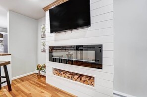 A modern living room with a flat-screen TV, built-in fireplace, and a dining area. - Pleasant Ridge 2BR Furnished Apartment | Extended Stay (Cincinnati)
