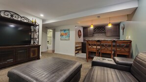 A living room with a large flat-screen TV, leather sofas, and a dining area with wooden chairs and a kitchen in the background. - Westy Escape 2 Living Rooms, 2 Primary Bedrooms, Bar, BBQ, FirePit, Patio (Westminster)