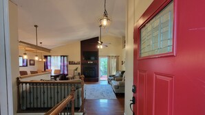 A spacious living area with a wooden staircase, a red door, and a fireplace. - Westy Escape 2 Living Rooms, 2 Primary Bedrooms, Bar, BBQ, FirePit, Patio (Westminster)