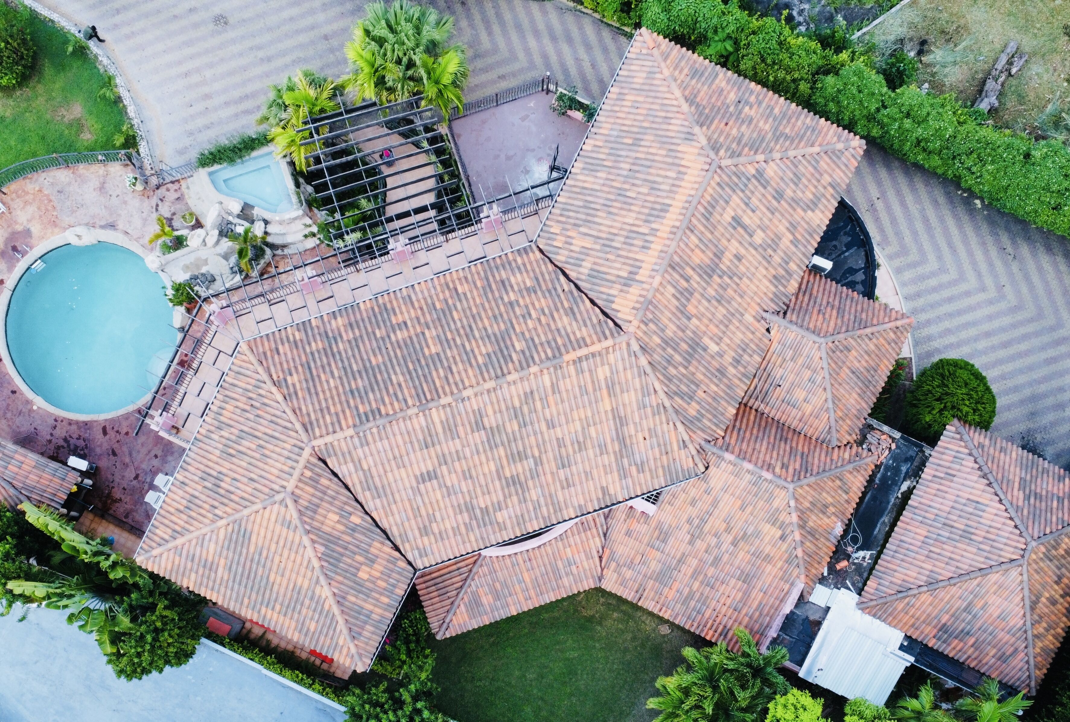 An aerial view of a property with a swimming pool, a covered patio, and a landscaped garden.