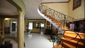Amplia sala de estar con una escalera curva, un gran pilar y vistas a la cocina.