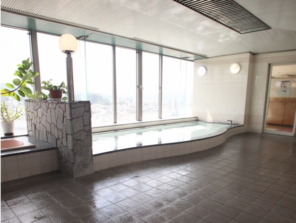A spacious indoor area with a large window, a stone feature, and a tiled floor.