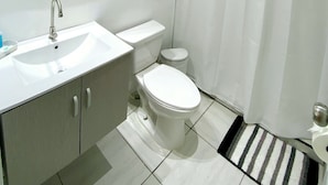 A modern bathroom with a white sink, toilet, and shower curtain. - Apartment Rio Nigua  (Salinas)