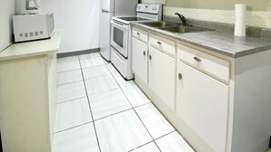 A compact kitchen with white cabinets, a built-in oven, a microwave, and a coffee maker. - Apartment Rio Nigua  (Salinas)