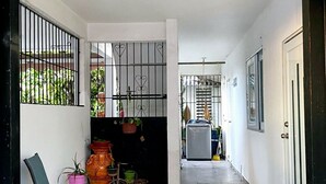 A corridor with tiled flooring, a chair, potted plants, and a bicycle. - Apartment Rio Nigua  (Salinas)