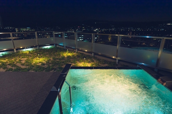 A rooftop pool with a city view at night.