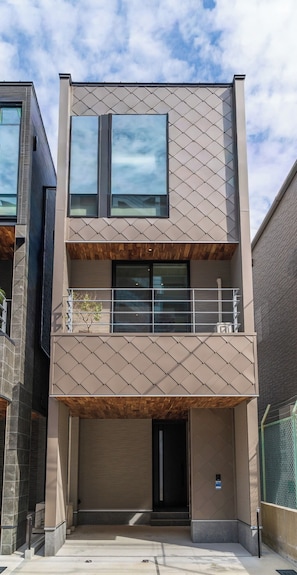 Un bâtiment moderne à deux étages, doté d’un balcon, de grandes fenêtres et d’une entrée de garage.