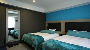 Una habitación de hotel con dos camas, un espejo grande y una pared de acento azul.