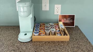 Una cafetera Keurig sobre una encimera de granito con un portal cápsulas de café que contiene varias cápsulas.