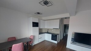 A modern kitchen with white cabinets, a black countertop, and a built-in dishwasher.