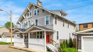 A two-story house with a front porch, a garage, and a red door.