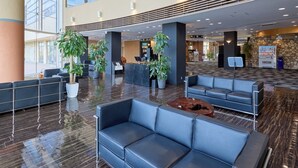 Eine geräumige Lobby mit Empfangstresen, Sitzbereichen und Topfpflanzen.