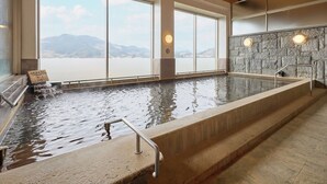 Ein großes Hallenbad mit Blick auf Berge, Steinwände und eine Holzdecke.