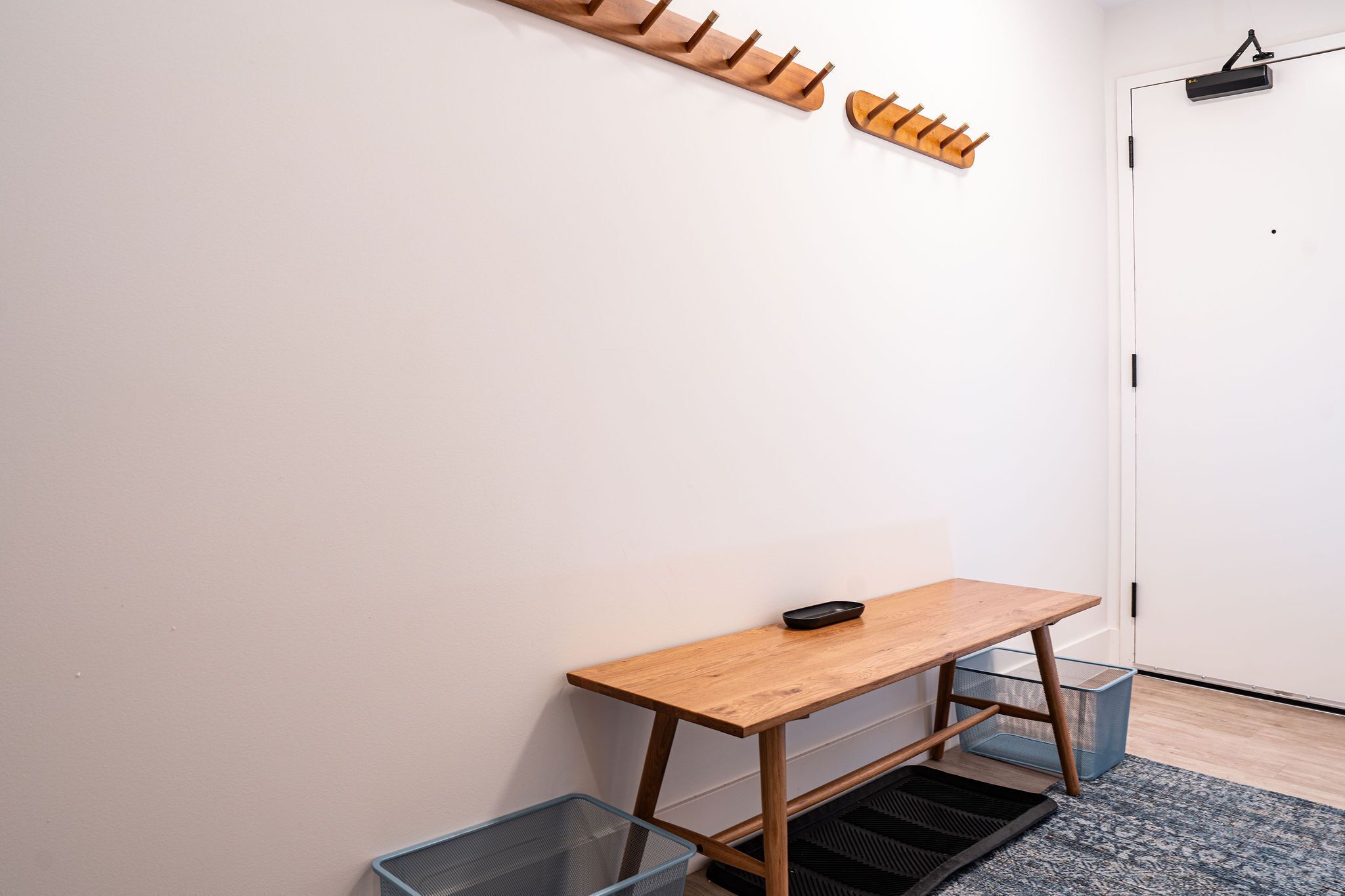A room with a wooden table, a coat rack, and a door.