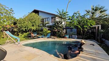 Una piscina al aire libre, sillones reclinables de piscina