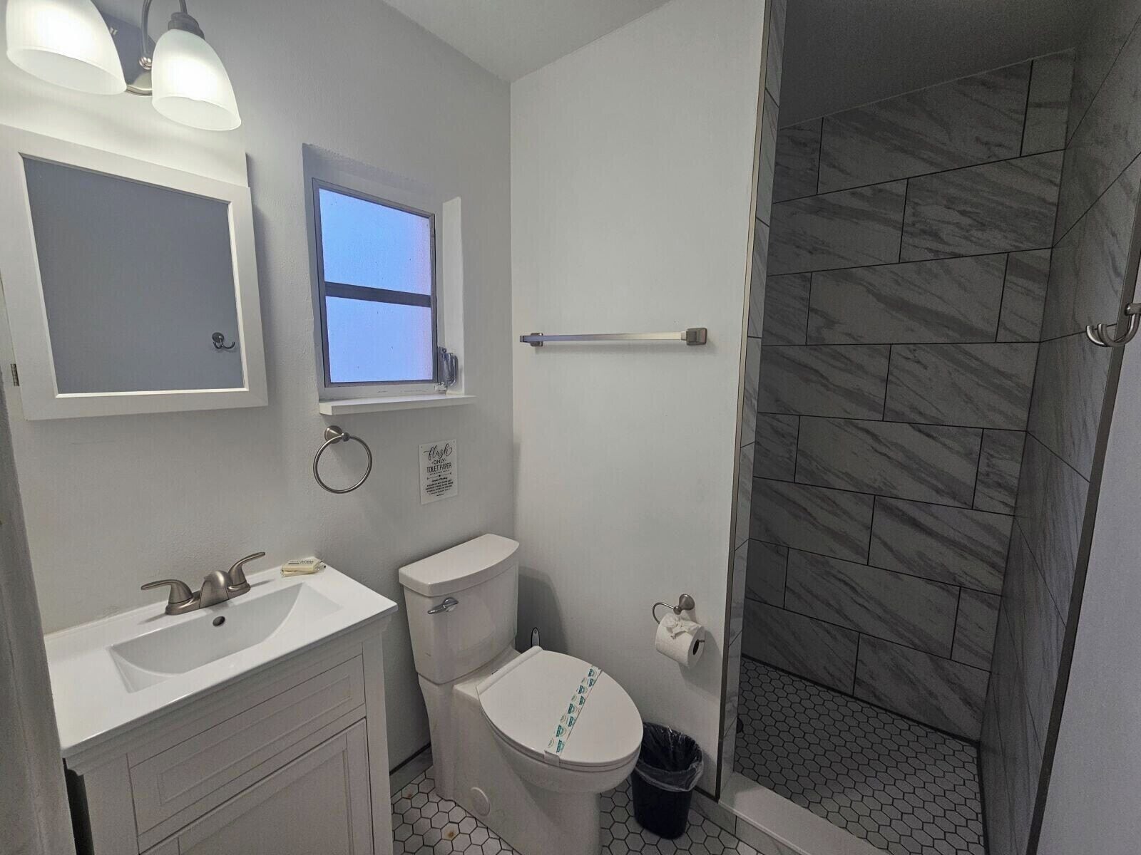 A bathroom with a toilet, sink, and a shower area.