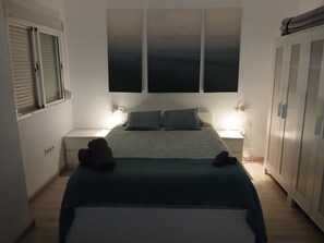 Ett sovrum med en säng, två sängbord, en garderob och ett fönster med persienner.