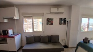 Un espacio habitable compacto con sofá, kitchenette y ventana con vistas al exterior.