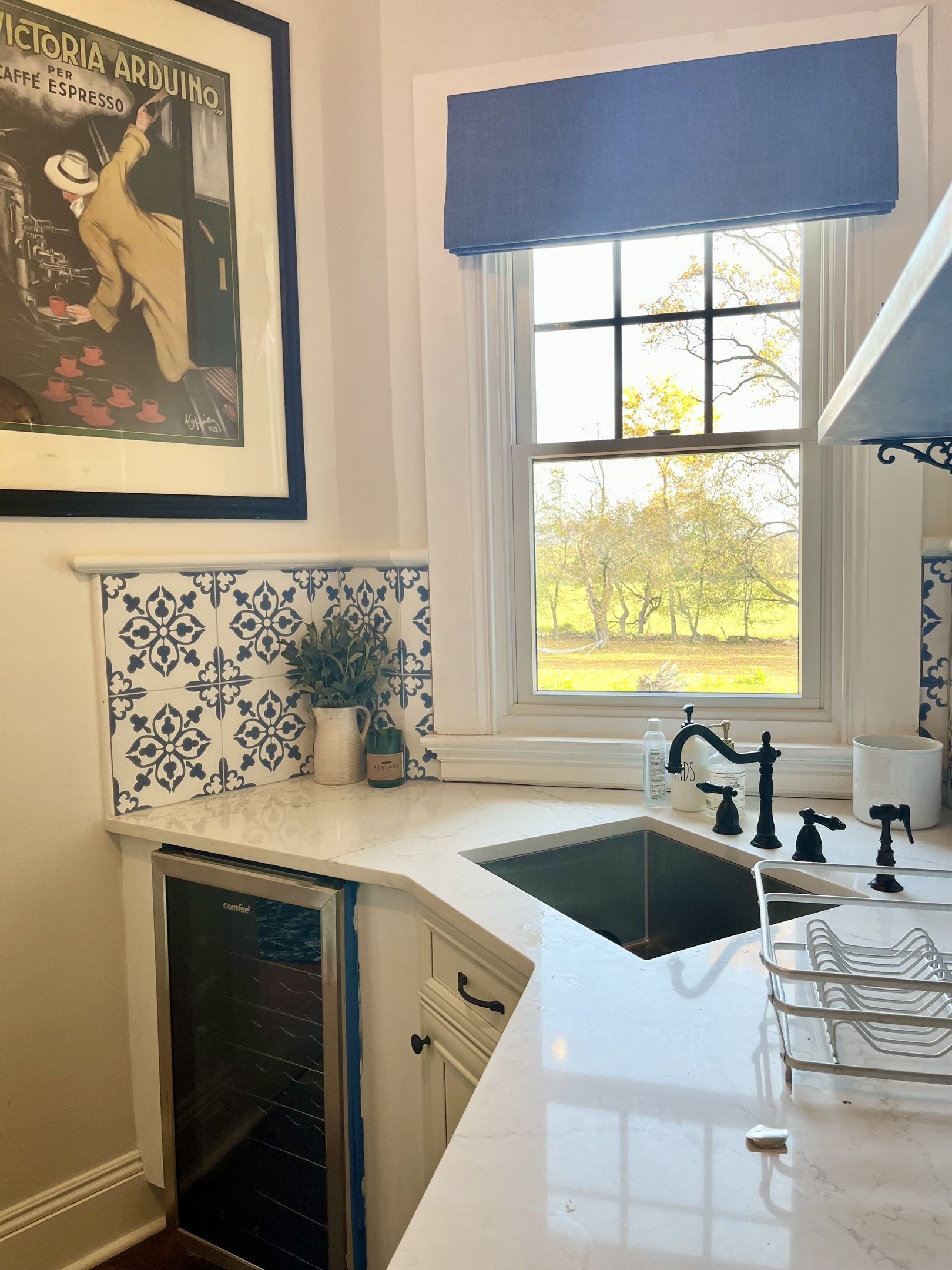 Una cocina con lavavajillas integrado, un ventanal con vista a árboles y un salpicadero decorativo.