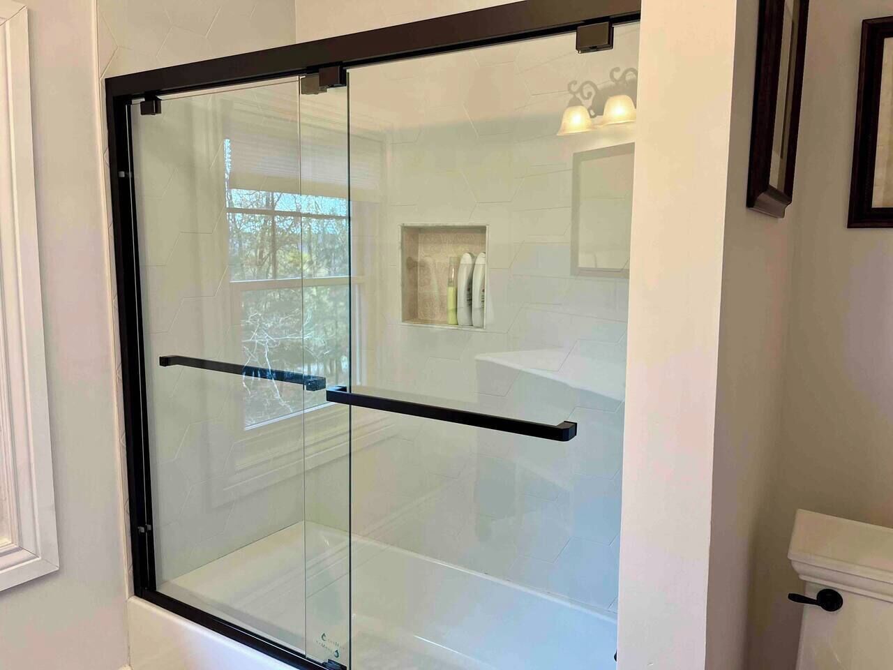 A modern bathroom with a glass shower enclosure, a white toilet, and a towel rack.