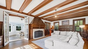 A spacious living room with a fireplace, a large white sectional sofa, and a dining area with a table and chairs. - Spectacular Historic Mansion w/Pool&Tennis (Goshen)