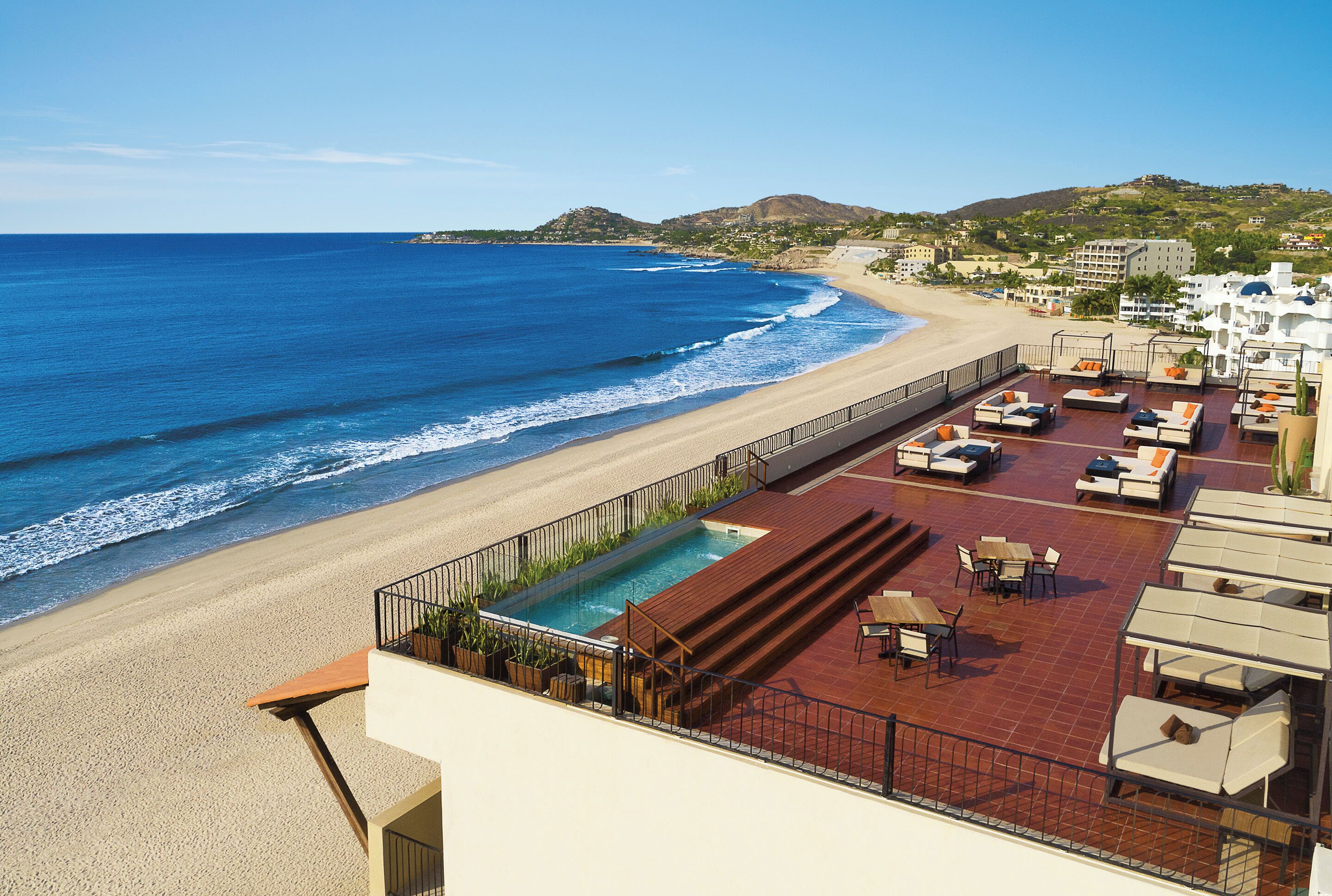 A rooftop pool area with a view of the beach and ocean.