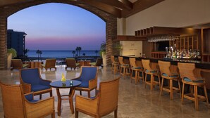 A bar area with wicker chairs and a view of the ocean at dusk. - Altitude by Krystal Grand Los Cabos – All Inclusive (San José del Cabo)
