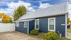 Une maison de plain-pied avec un toit en métal, une clôture blanche et le chiffre « 2013 » peint sur le côté.