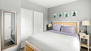 Une chambre à coucher comprenant un lit, des tables de chevet, une armoire et des œuvres d’art murales.