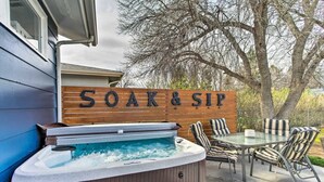 Ein Whirlpool mit einem Holzschild, auf dem 'SOAK & SIP' steht, in einem Garten.