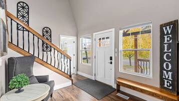 Un intérieur moderne avec un escalier, un banc, une pancarte de bienvenue et une porte dotée d’une fenêtre.