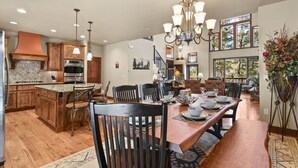 Una cocina amplia con armarios de madera, una isla grande y una zona de comedor con una mesa larga y sillas.