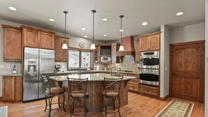 Una cocina amplia con gabinetes de madera, electrodomésticos de acero inoxidable y una isla central con taburetes de bar.