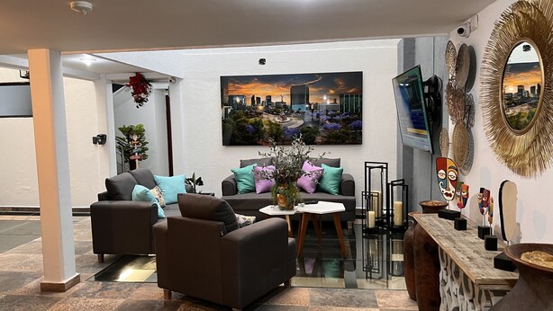 A modern living room with a cityscape painting, a television, and decorative items. - Pukas, a cuatro cuadras del Ángel de Reforma (Mexico)