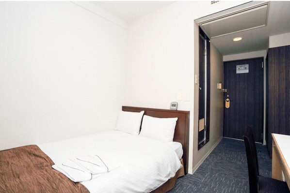 Comfortable room with a neatly made bed, wooden headboard, and a small table with a chair.