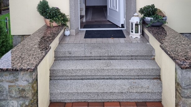 A building entrance with a set of steps leading to a door, a small window, and a potted plant on the left. - Ferienwohnung mit Balkon im Wunderschönen Tecklenburg, Wanderwege (Tecklenburg)