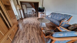 A living room with a sofa, chairs, a coffee table, and a TV. - Ferienwohnung mit Balkon im Wunderschönen Tecklenburg, Wanderwege (Tecklenburg)