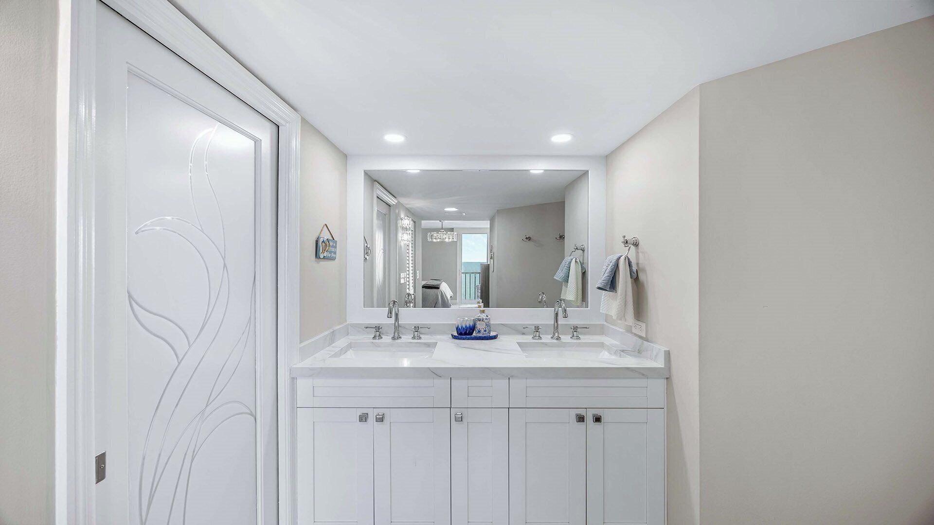 A modern bathroom with a double sink, a large mirror, and a walk-in closet.