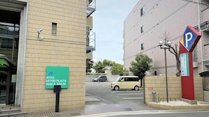 Une enseigne d’hôtel pour l’ASTON PLAZA OSAKA SAKAI, un panneau indiquant un parking et un bâtiment à la façade recouverte de carreaux.