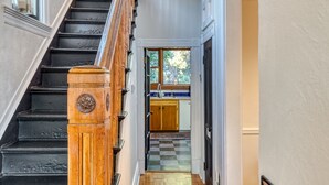 A staircase leading to a kitchen with wooden cabinets and a checkered floor.