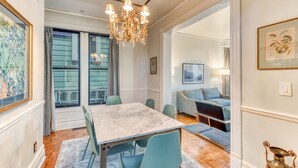 A dining area with a marble table, teal chairs, and a chandelier.