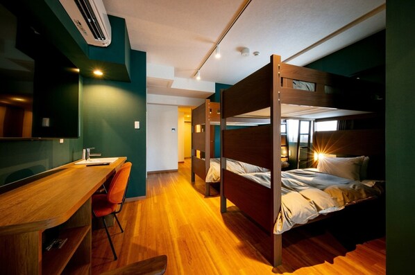 Une chambre avec un lit superposé, un bureau et une chaise, un plancher en bois et un appareil de climatisation visible.