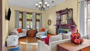 Amplia sala de estar con dos sofás, una mesa de centro, chimenea y candelabro.