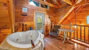 Interior d'una cabana de fusta amb una banyera d'hidromassatge, una cadira i una taula petita.