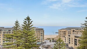A coastal hotel with multiple floors, a beach view, and a pedestrian bridge.