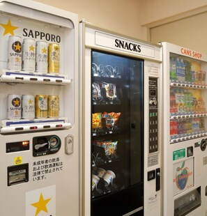 Automatdisk med skilte 'Sapporo', 'Snacks' og 'Dåsebiks', der sælger forskellige drikkevarer og snacks.